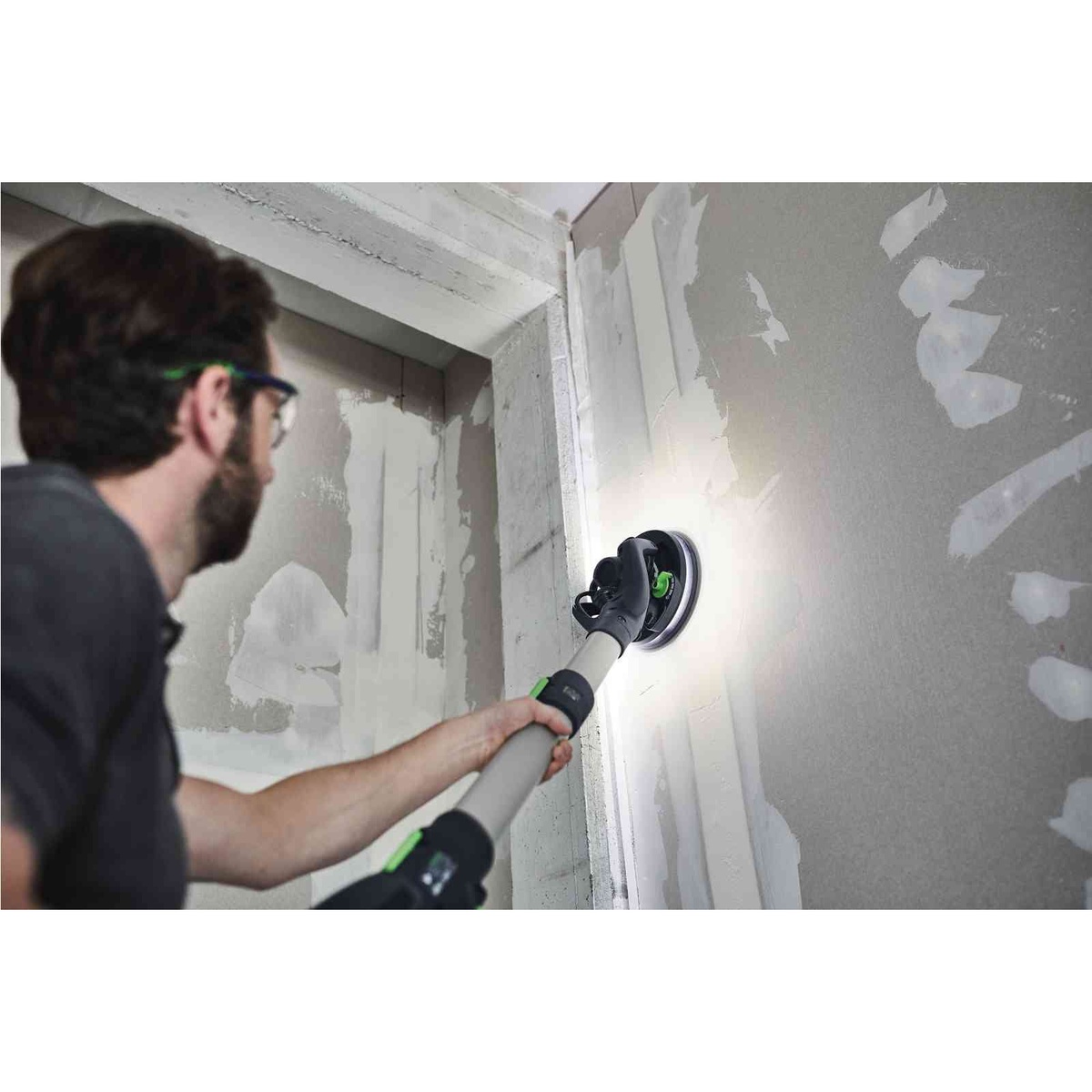 Festool 575994 Planex 2.0 Drywall Sander + CT 36 EI AutoClean Dust Extractor Bundle sanding a drywall wall in a remodel space with the LED light ring revealing uneven joint compound