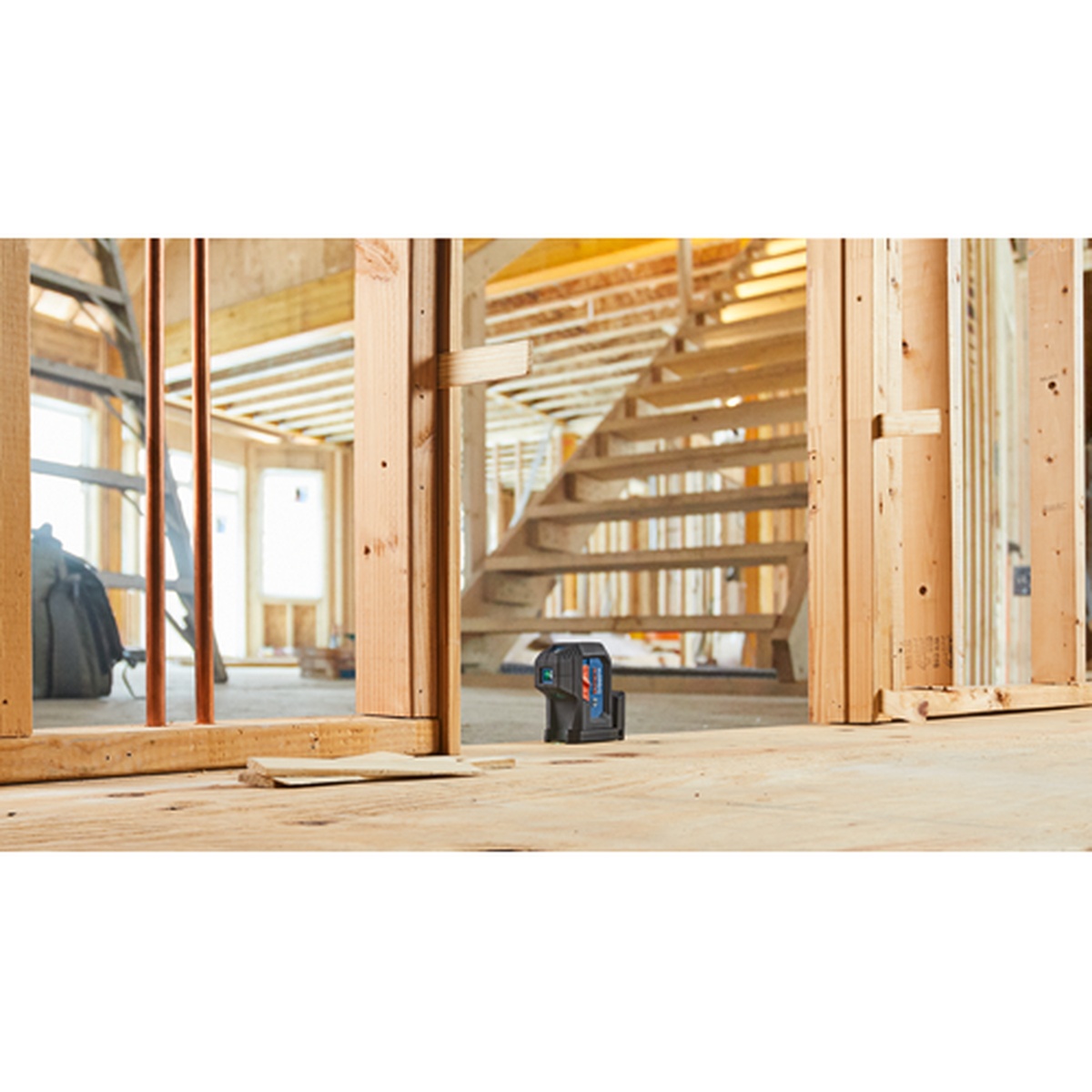 Bosch GPL100-30G Green-Beam Three-Point Self-Leveling Alignment Laser set on a framed wood floor inside a residential construction jobsite