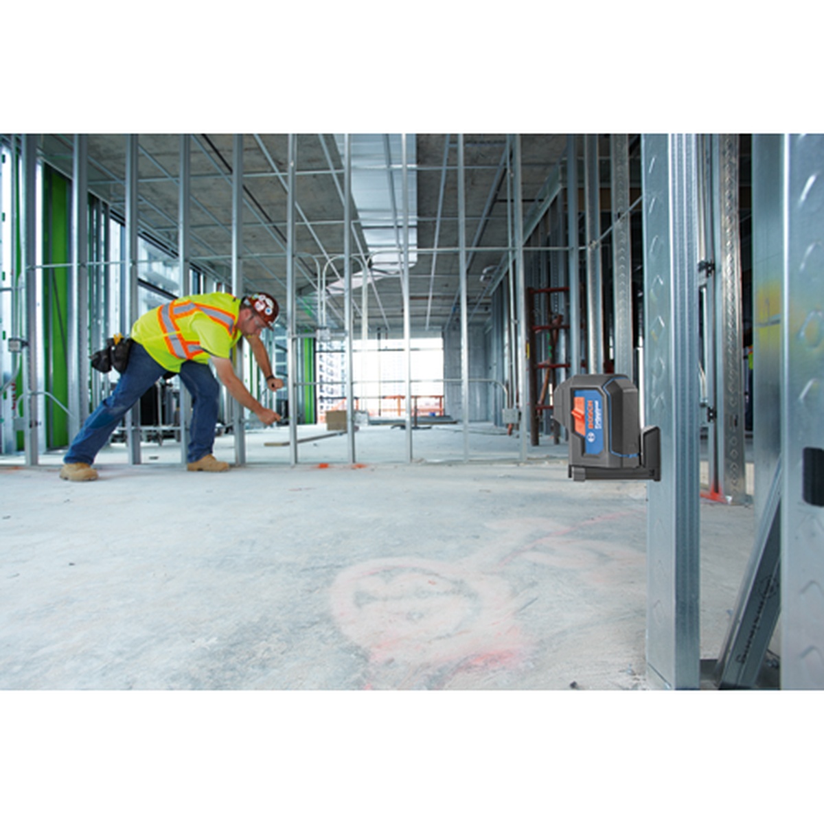 Bosch GPL100-30G Green-Beam Three-Point Self-Leveling Alignment Laser projecting layout points on a commercial interior floor during metal stud framing work
