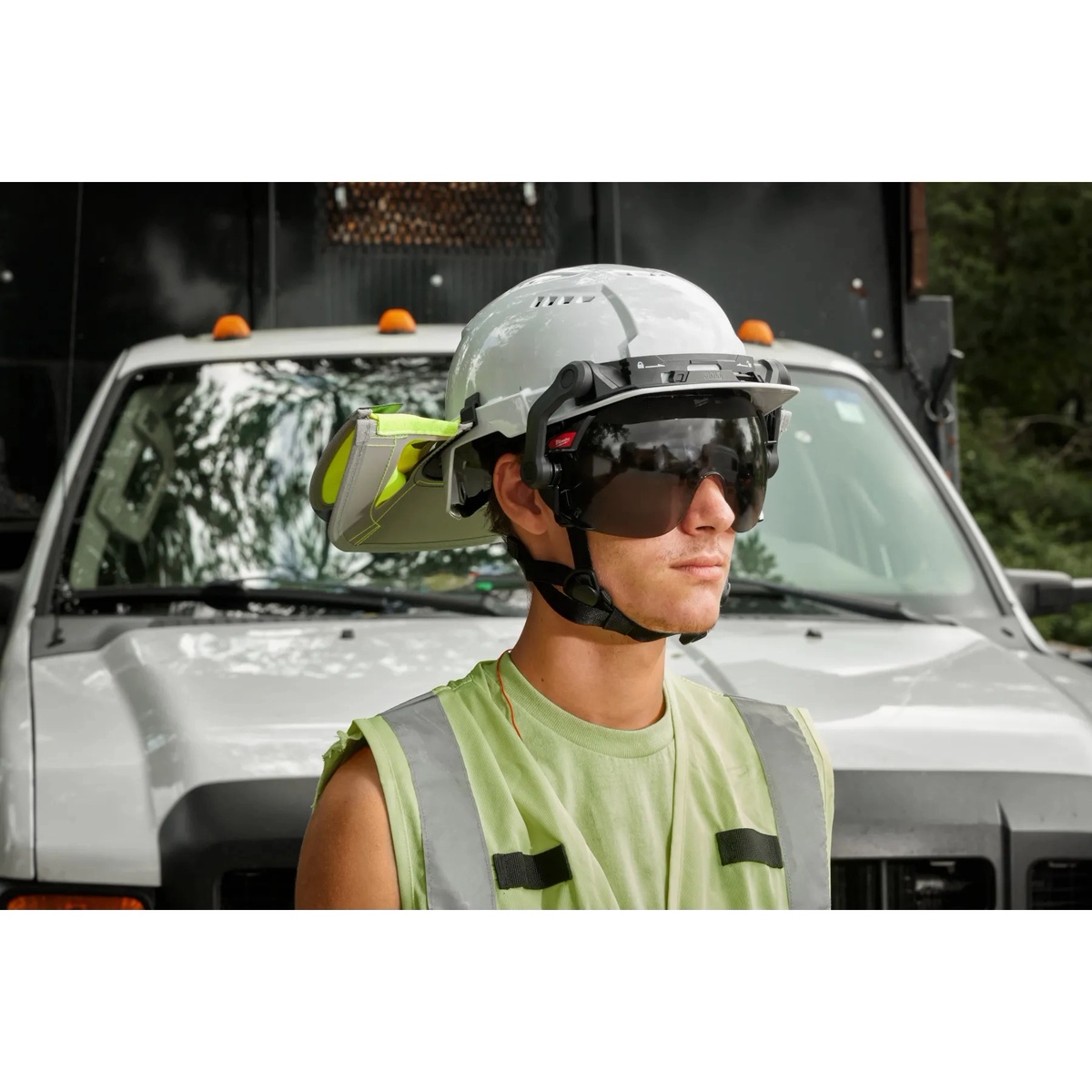 Milwaukee 48-73-1328 safety helmet worn on a jobsite in front of a work truck with mounted hearing protection and face protection accessories