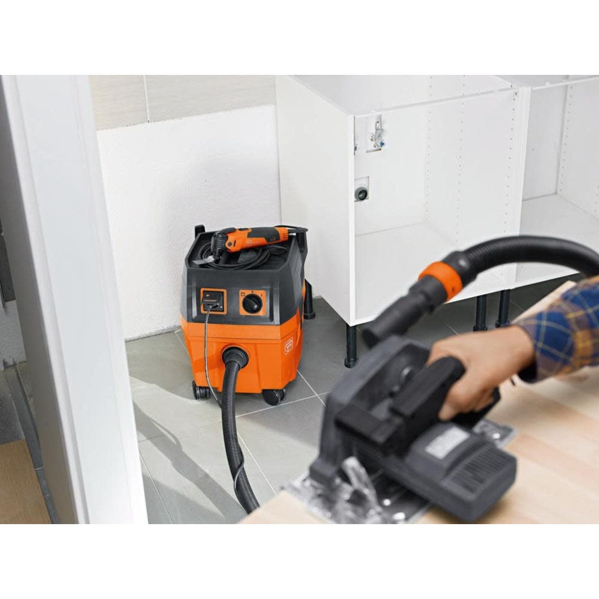Fein 92035236090 Corded TURBO I 5.8 Gal. Wet/Dry Dust Extractor collecting dust from a circular saw while positioned in a tight interior cabinet installation area