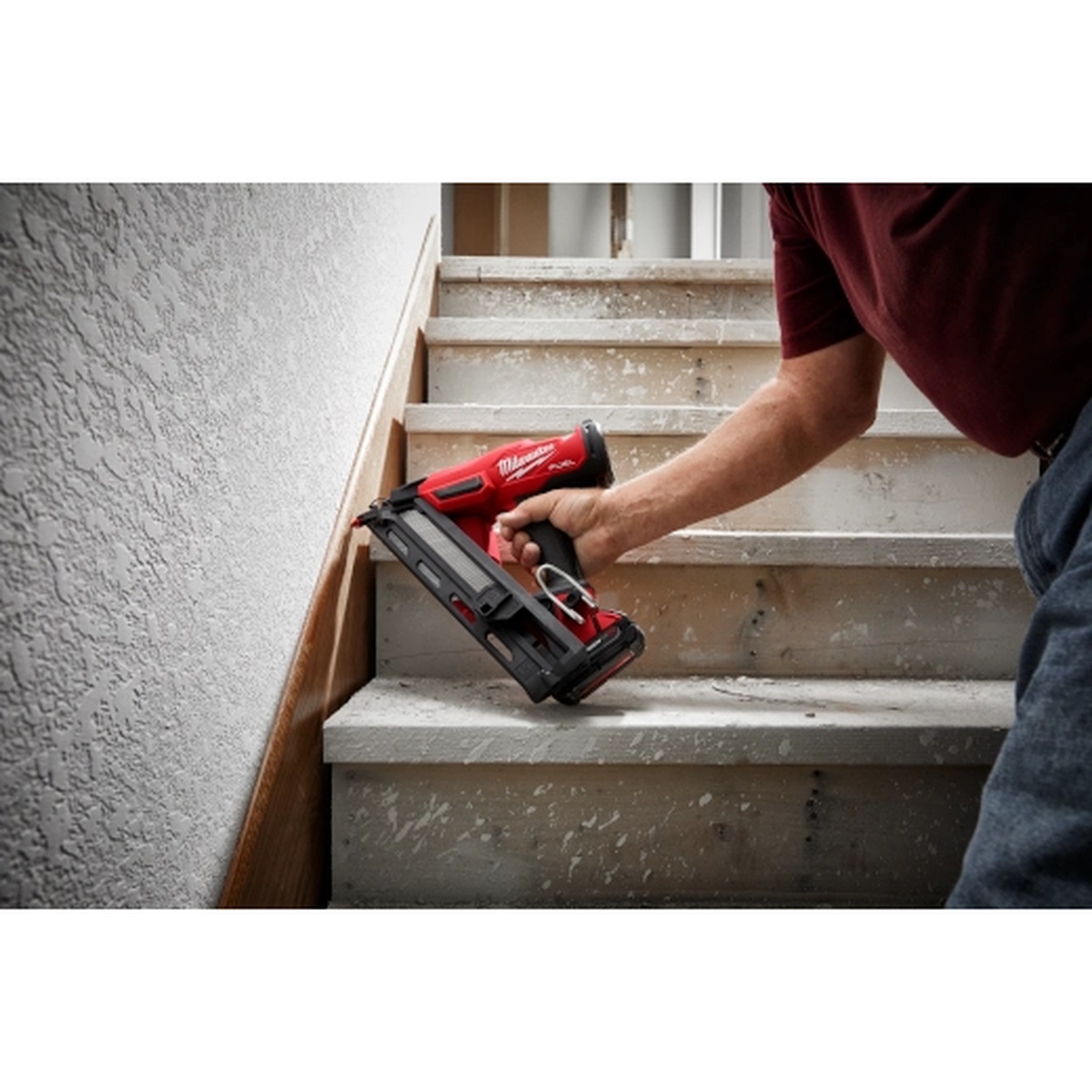 Milwaukee 2839-21CT M18 FUEL 15 Gauge Finish Nailer Kit fastening trim on a stair skirt in a finished interior stairwell during remodeling work