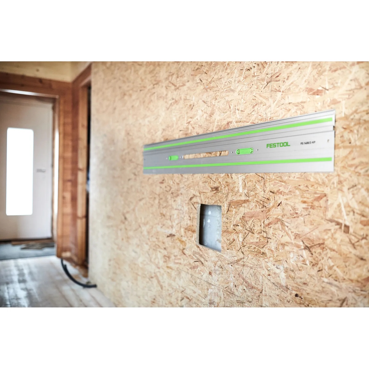 Festool 577044 75-in Guide Rail, FS 1900/2-KP mounted on an OSB wall surface for straight cutting and layout work in an interior jobsite setting