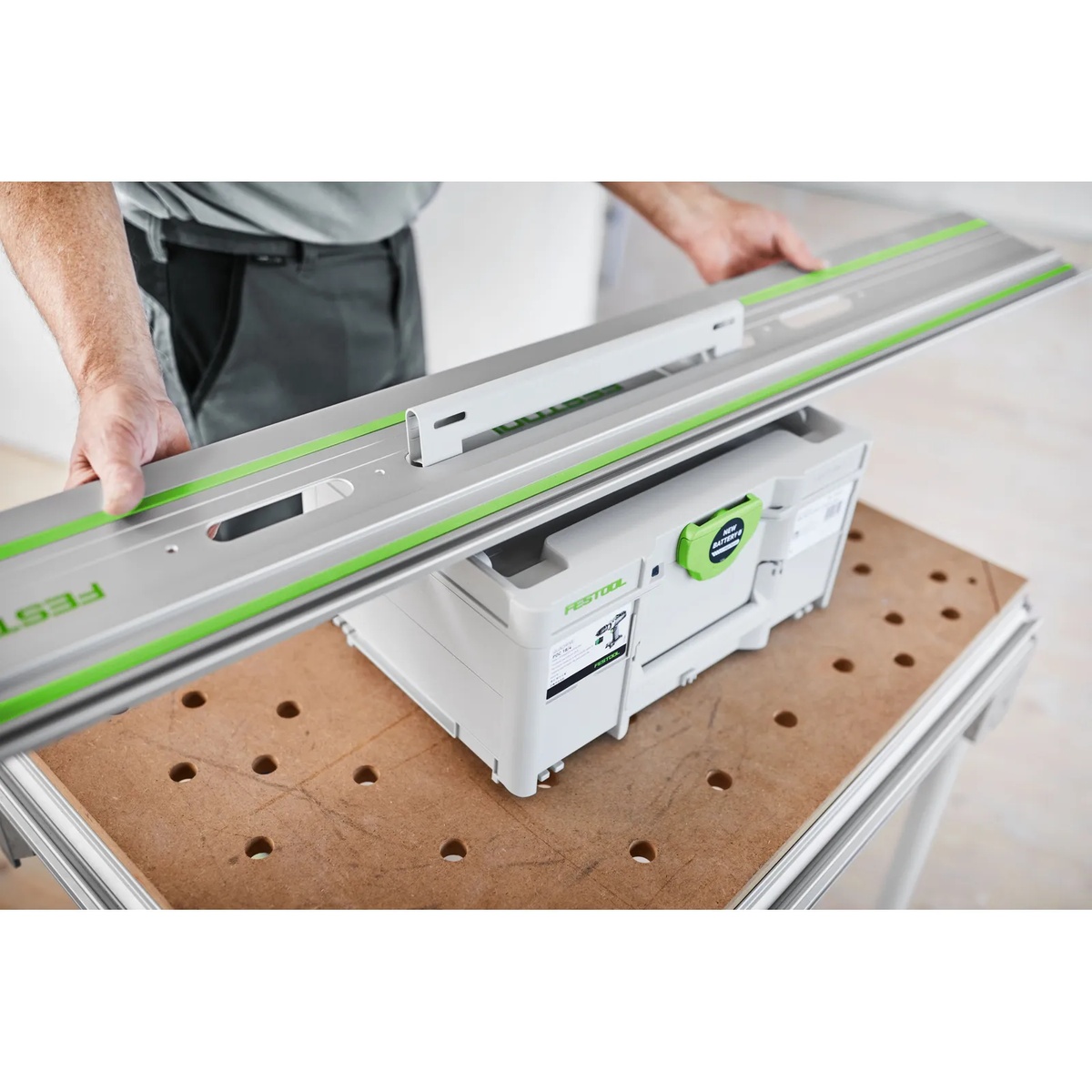 Festool FS 1900/2-KP guide rail positioned over a Festool Systainer on a workbench, showing how the rail is carried and stored for transport between jobs