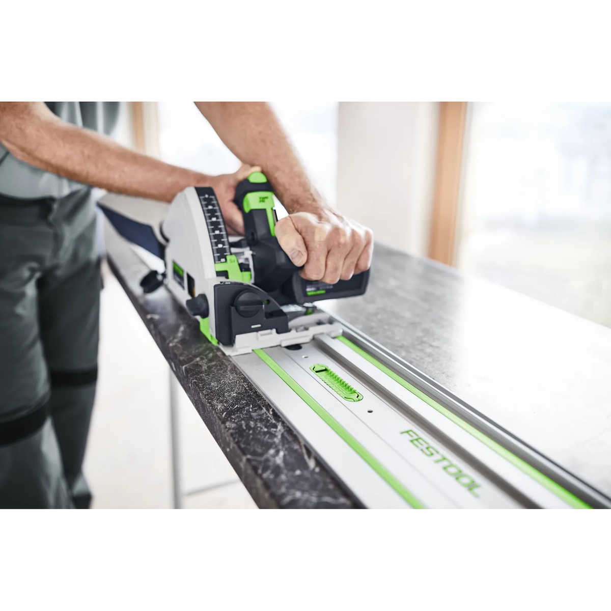 Festool guide rail in use with a track saw on a dark countertop, showing the FS 1900/2-KP guiding a straight cut on finished material