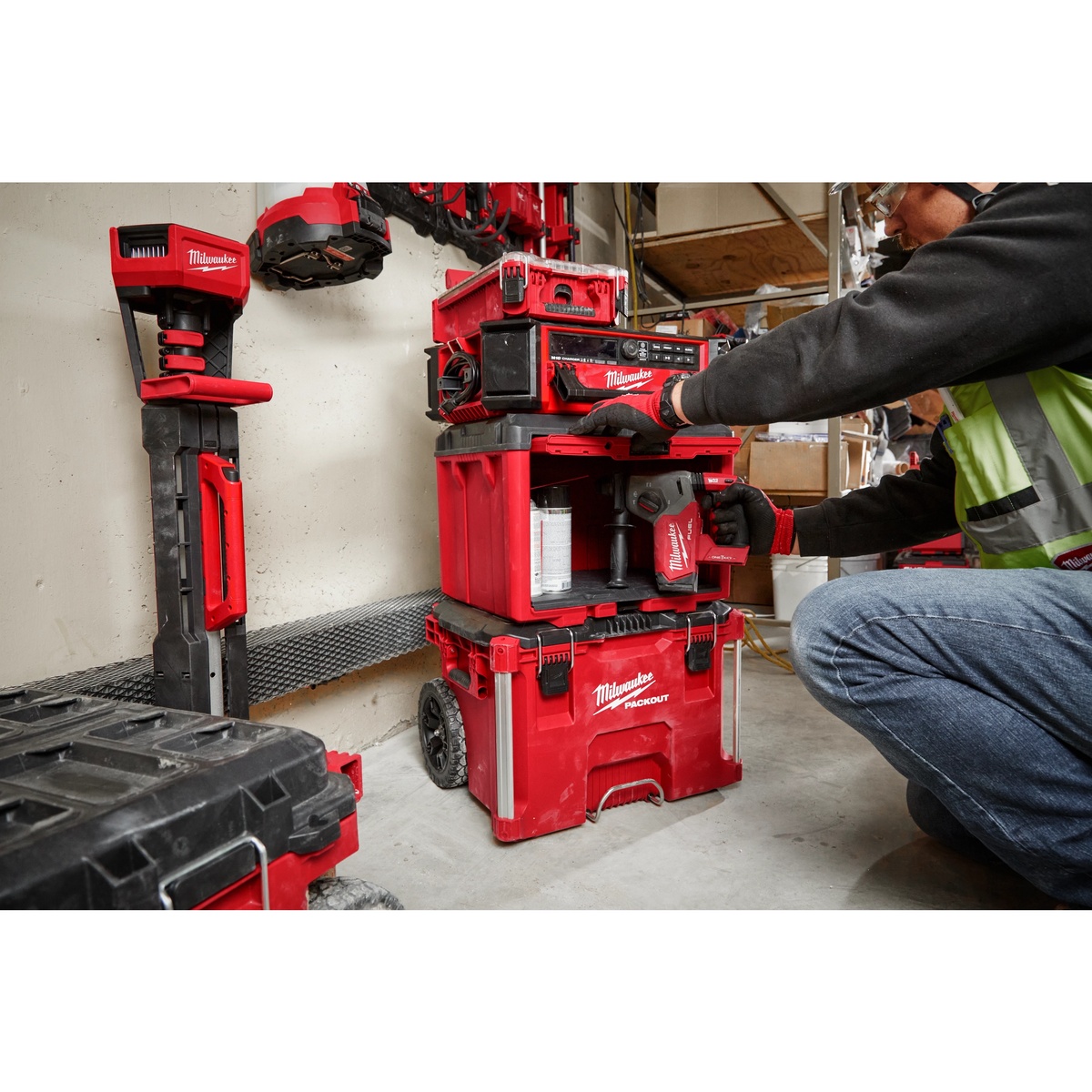 Milwaukee PACKOUT cabinet used in a stacked mobile storage setup holding a rotary hammer and supplies on a jobsite floor