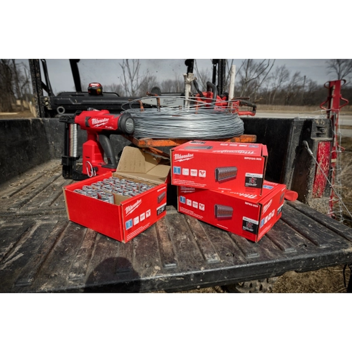 Milwaukee MPU112-960 1.5 Inch 9 Gauge Galvanized Staples with utility fencing stapler and fencing wire on a jobsite truck bed during outdoor fence installation