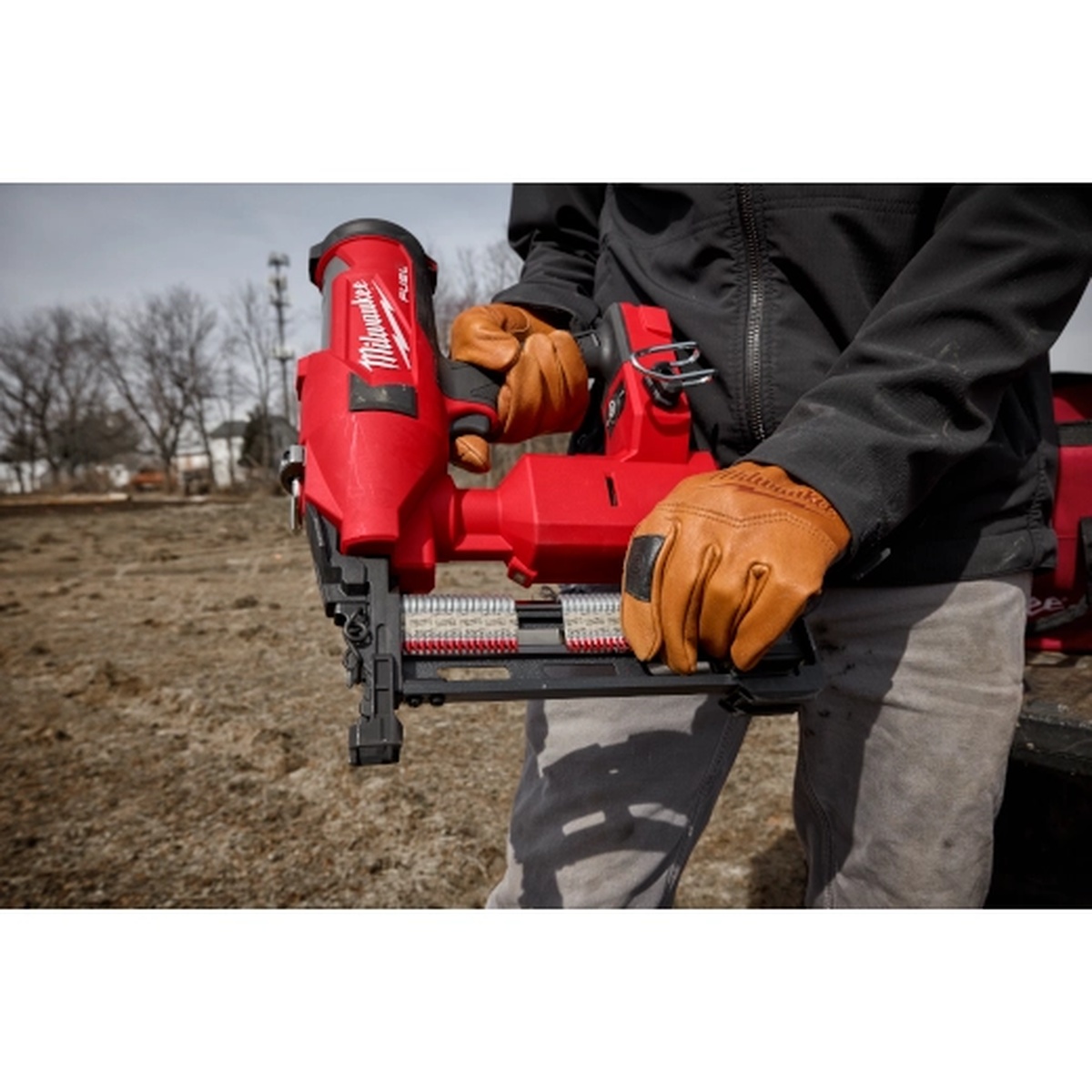 Milwaukee M18 FUEL Utility Fencing Stapler being loaded with Milwaukee MPU112-960 1.5 Inch 9 Gauge Galvanized Staples in an outdoor work setting