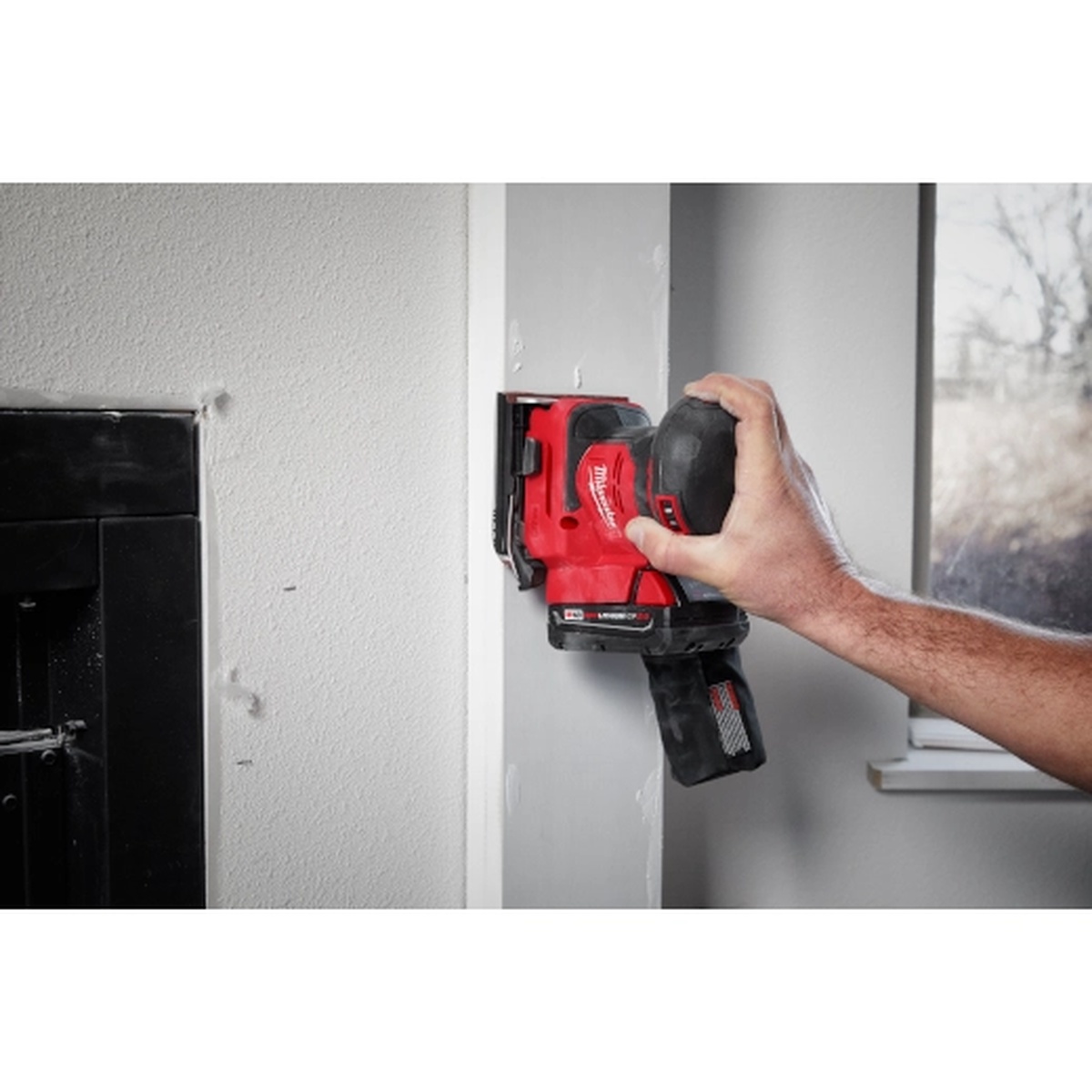 Milwaukee 2649-20 M18 Orbital 1/4 Sheet Sander smoothing an interior wall corner during surface preparation