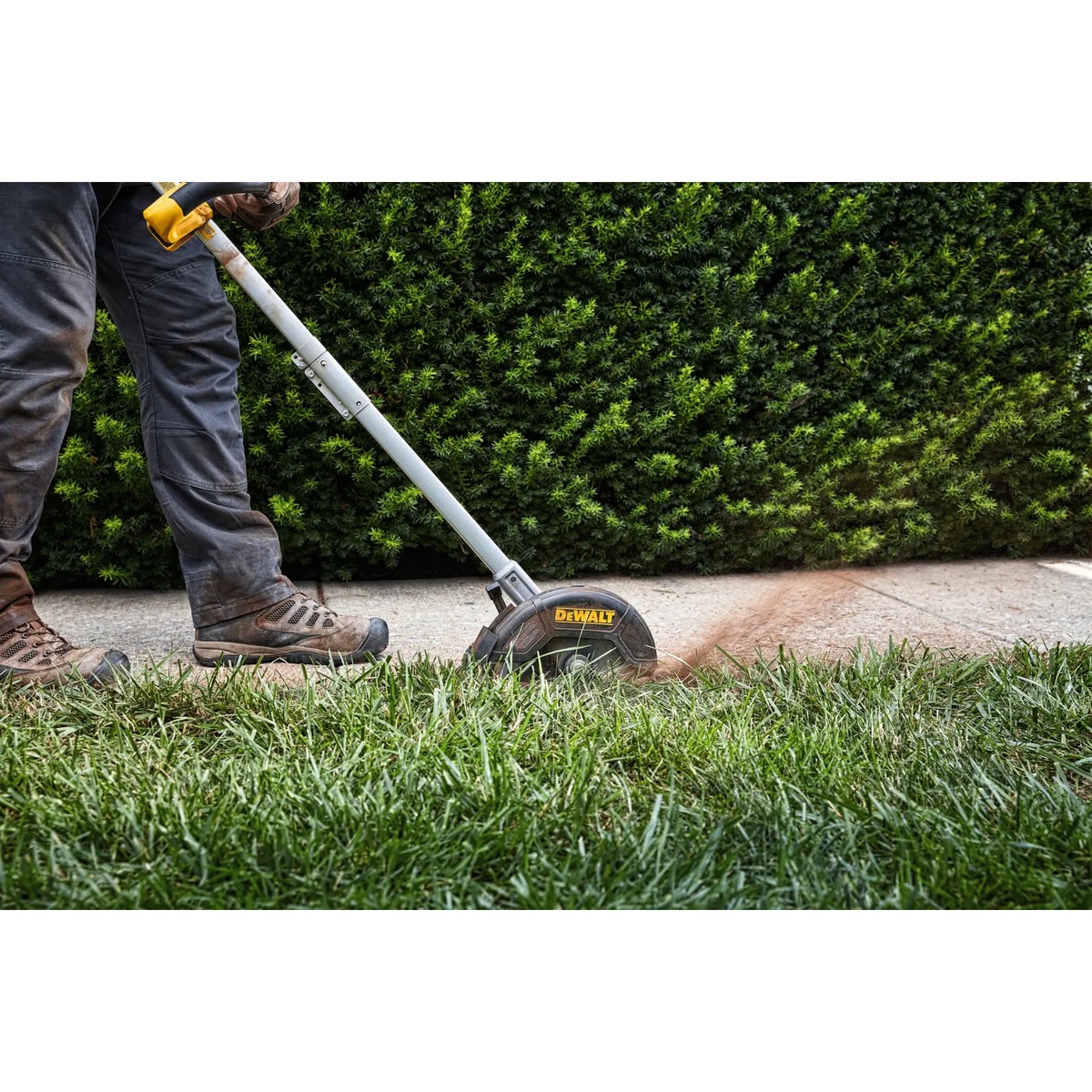 DEWALT 20V MAX Brushless Cordless Edger digging a defined trench edge through grass next to a paved walkway