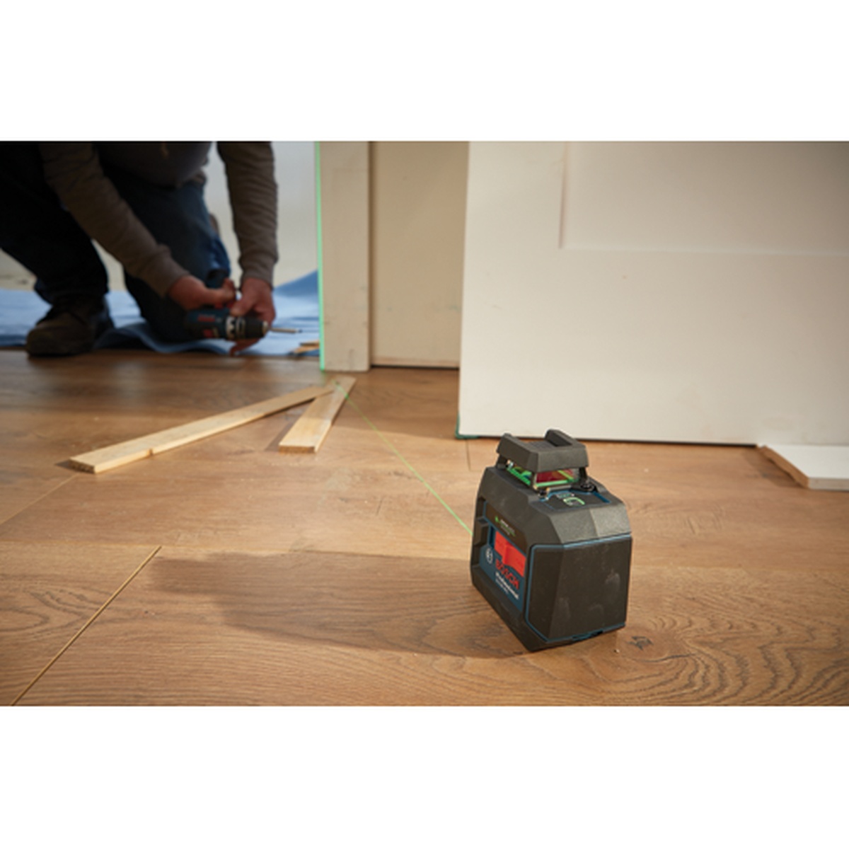 Bosch GLL50-40G Green-Beam Self-Leveling 360° Cross-Line Laser on a floor during doorway layout and interior construction work