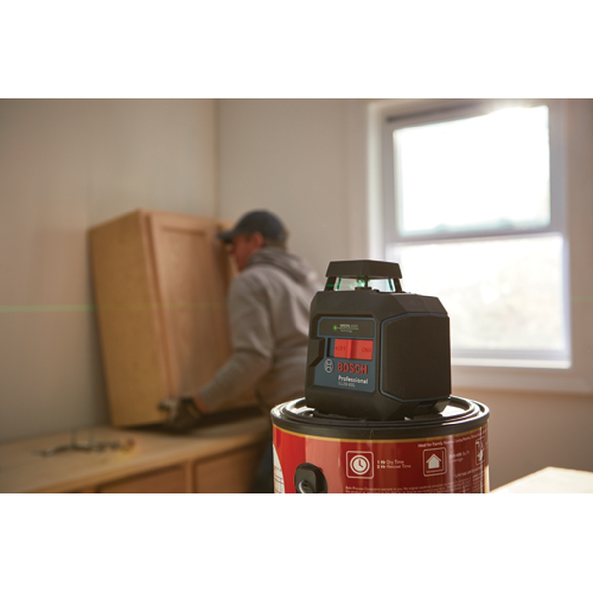 Bosch GLL50-40G Green-Beam Self-Leveling 360° Cross-Line Laser set up in a kitchen remodel space projecting a visible green level line for cabinet installation
