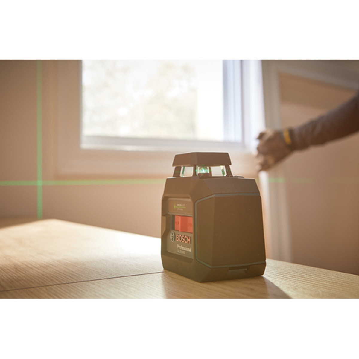 Bosch GLL50-40G Green-Beam Self-Leveling 360° Cross-Line Laser projecting a level horizontal and vertical line across an interior room for remodeling layout work