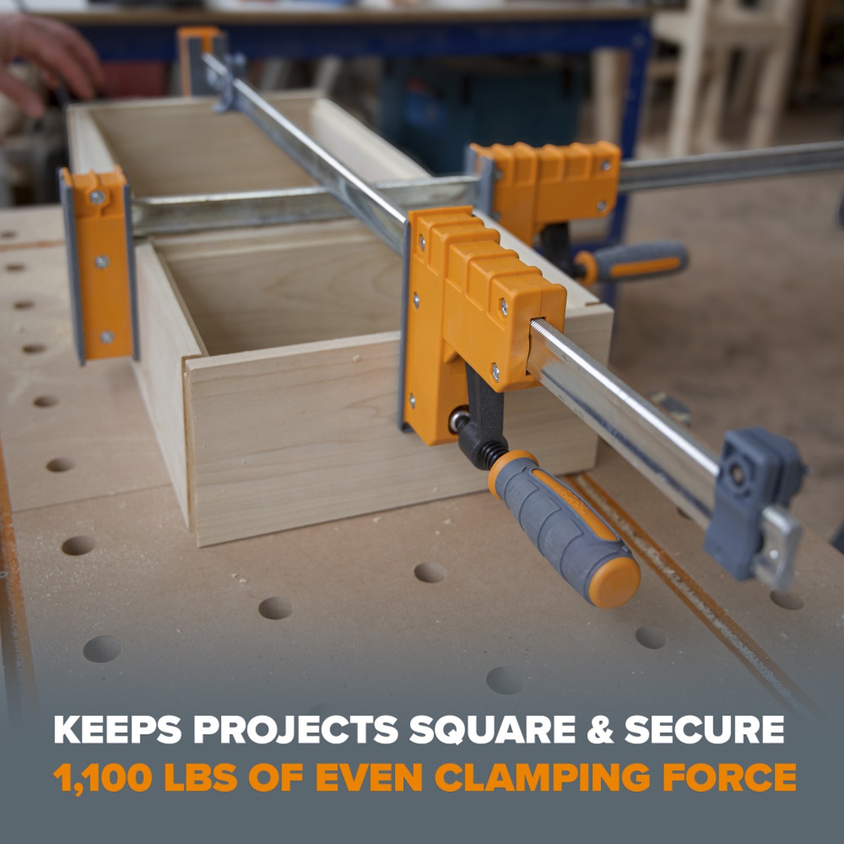 Bora parallel clamps holding a wood cabinet box square on a perforated workbench during assembly, showing even clamping force across the project