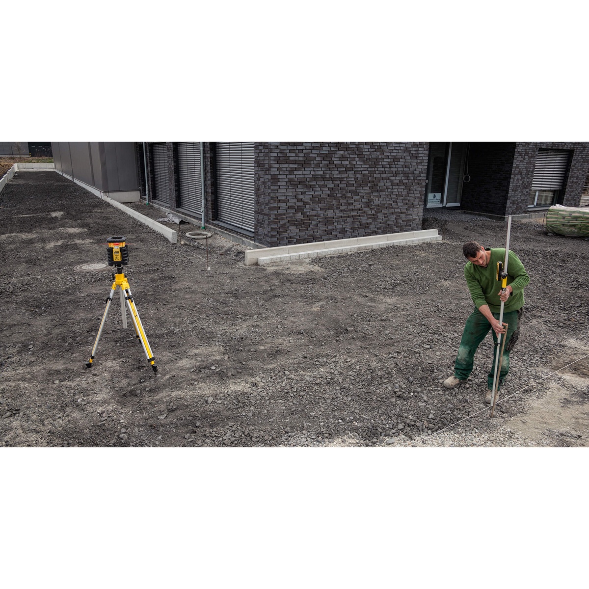 Stabila REC 300 Digital Receiver used on a construction site for grading and laser layout beside a tripod-mounted laser and grade rod