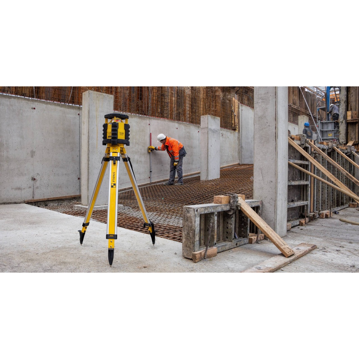 Stabila 07469 Hi-Lo Elevation Rod with slide carriage receiver bracket mount used alongside a tripod-mounted construction laser on a concrete wall layout