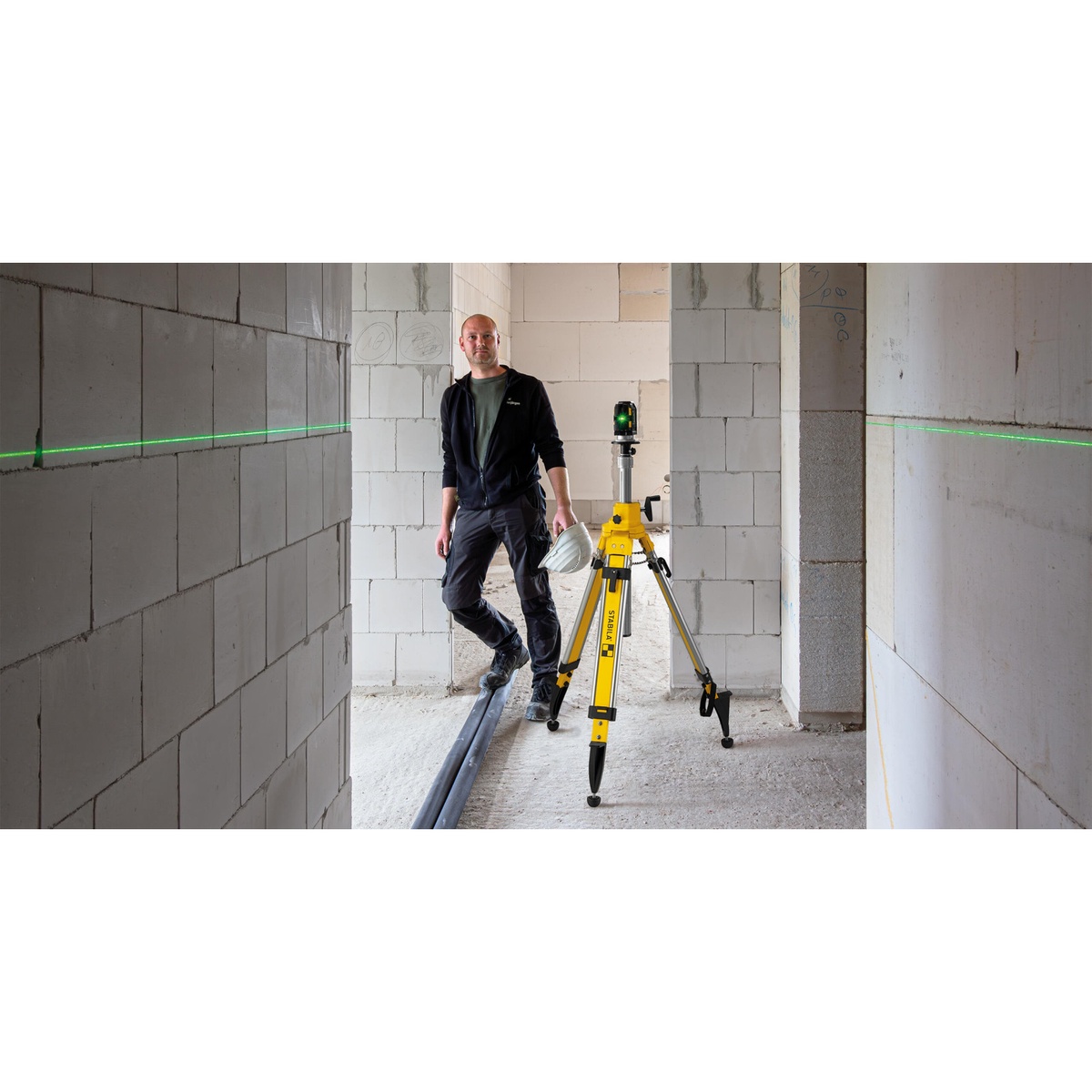 Stabila 08560 tripod supporting a laser level in a narrow unfinished hallway for interior wall layout work