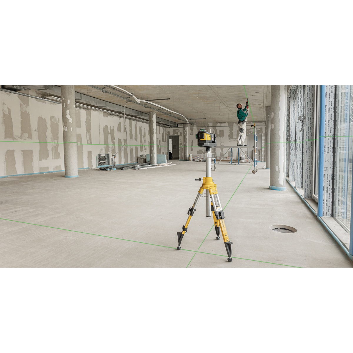 Stabila 08560 tripod holding a laser level in a large commercial interior for floor and wall layout alignment