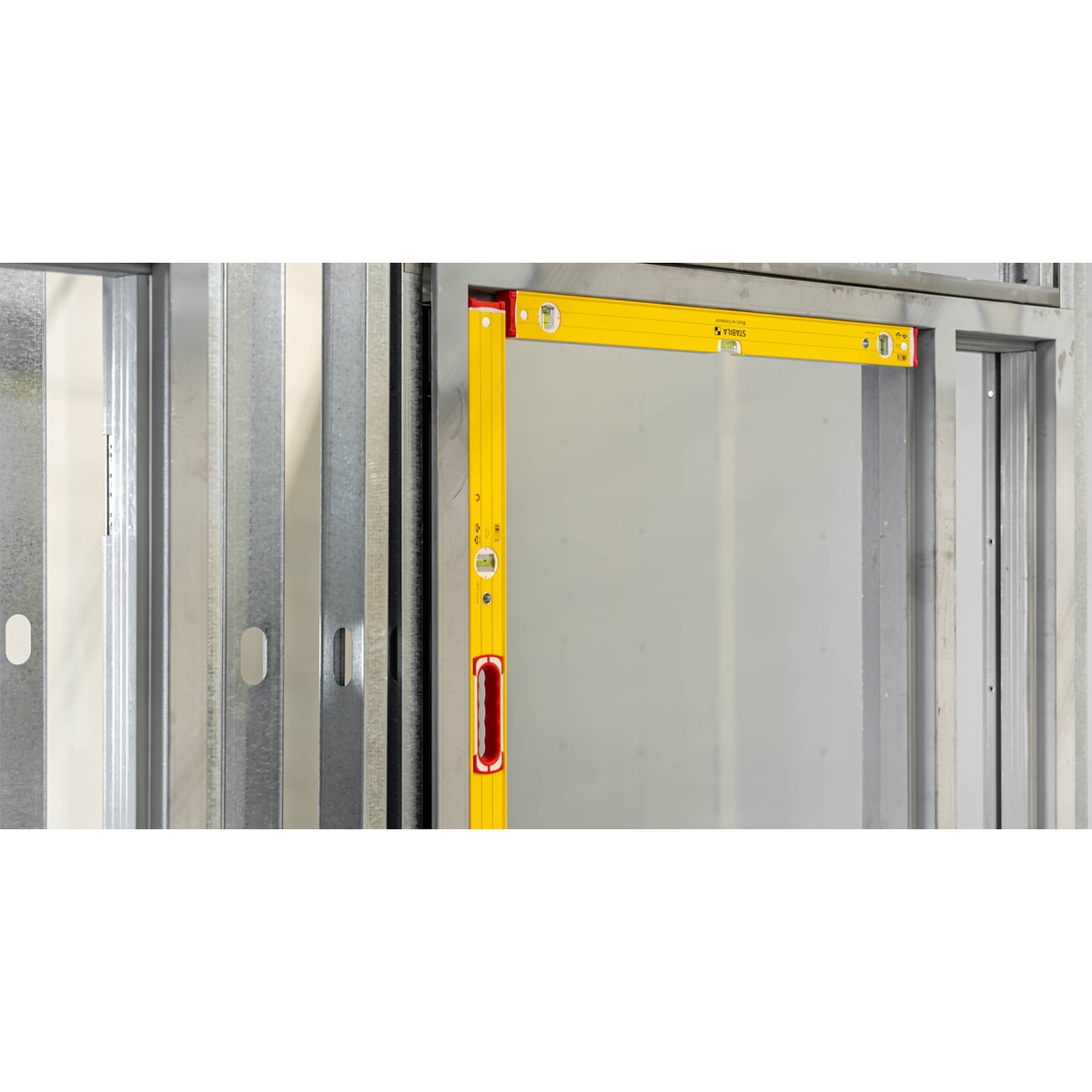 Stabila Type 96M magnetic level checking plumb and level on a metal stud frame corner during interior wall installation