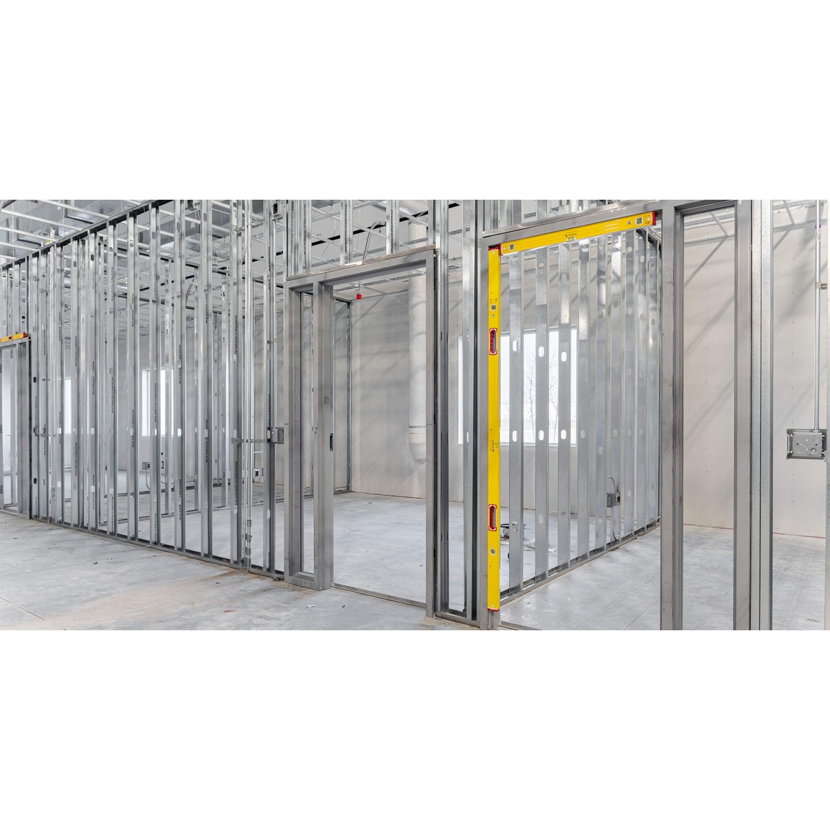 Stabila Type 96M magnetic level attached to metal stud framing during door opening layout on an interior construction jobsite