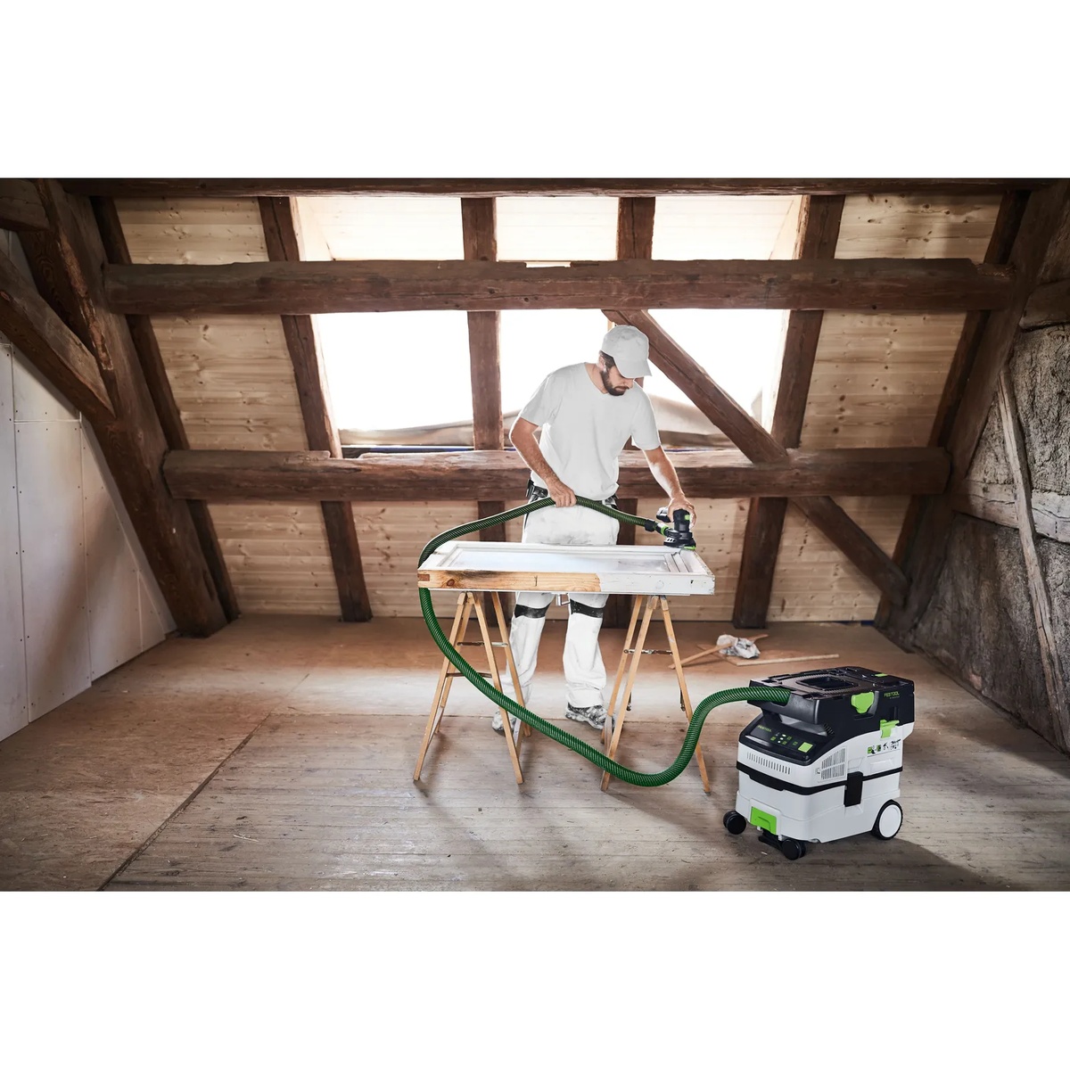 Festool cordless mobile dust extractor connected to a sander while finishing a door panel in an attic remodel workspace