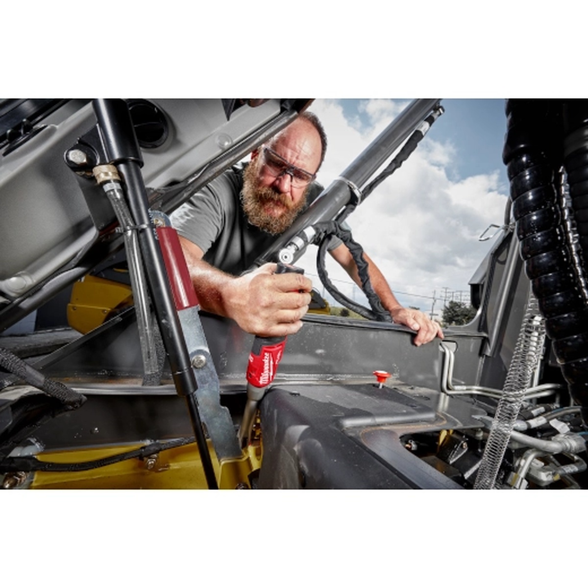 Milwaukee M12 FUEL 1/4 inch Extended Reach High Speed Ratchet being used inside an engine bay to reach a fastener in a tight automotive service area