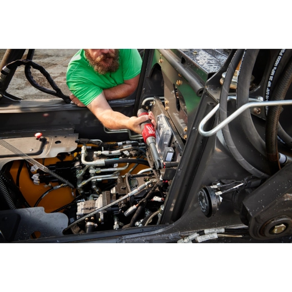 Milwaukee M12 FUEL 3/8 in Extended Reach High Speed Ratchet being used inside a heavy equipment service compartment to run fasteners in a cramped maintenance area