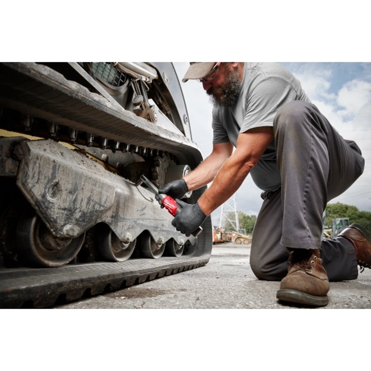 Milwaukee M12 FUEL 3/8 in Extended Reach High Speed Ratchet servicing track equipment outdoors, showing cordless mobility and low-clearance access