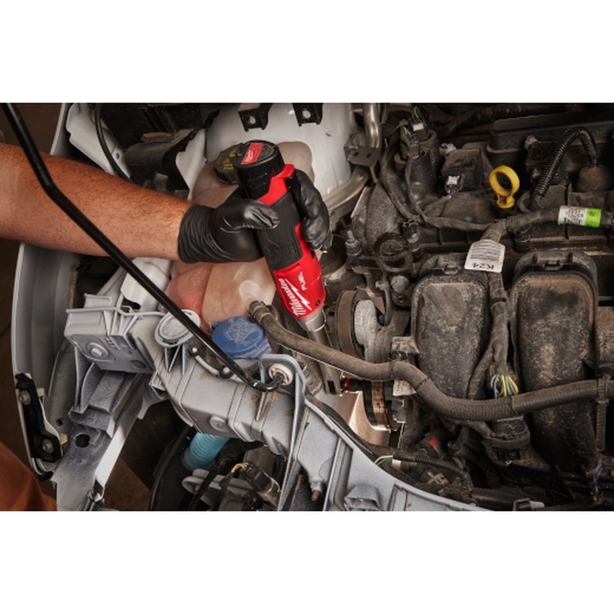 Milwaukee M12 FUEL 3/8 in Extended Reach High Speed Ratchet fastening in a crowded engine bay, highlighting compact body control and service access