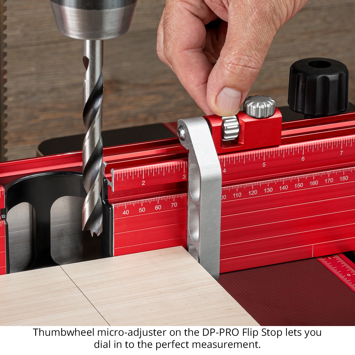 Woodpeckers DPPRO-FSTP DP-PRO Flip Stop mounted on the DP-PRO fence beside a drill bit for repeat woodworking drilling setup on a drill press table