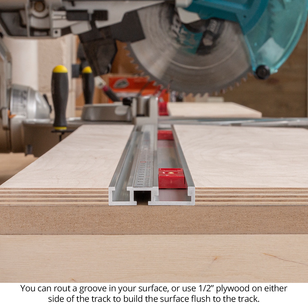 Woodpeckers StealthStop track mounted flush into a miter saw table surface between plywood work supports for woodworking cut station use