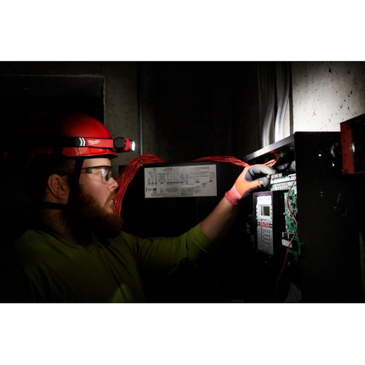 Milwaukee 2163-21 REDLITHIUM USB 600-Lumen Hard Hat Headlamp being used for electrical panel work in a dark indoor jobsite setting