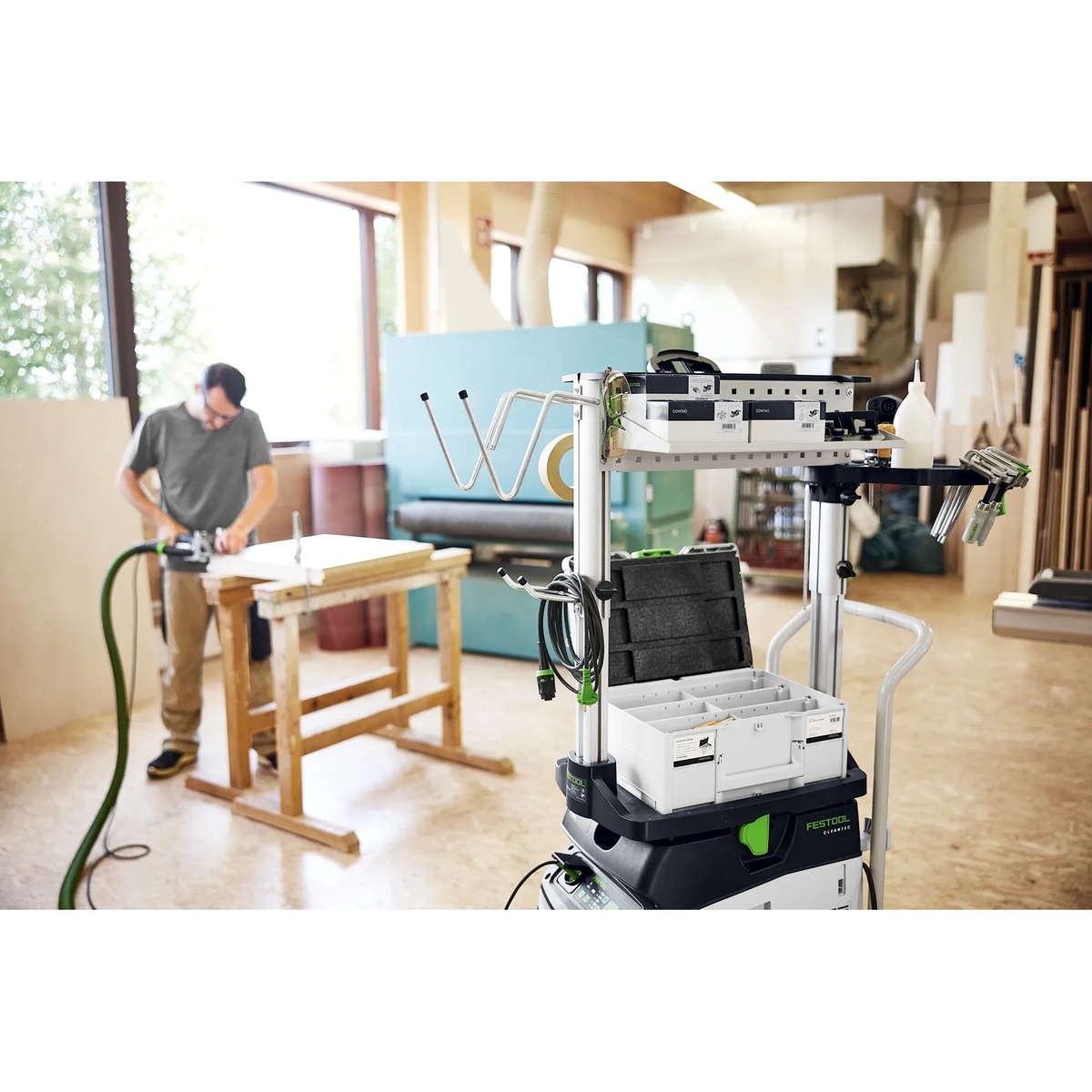 Festool workcenter organizer loaded with accessories and cords beside a woodworking bench in a shop for mobile task-ready storage