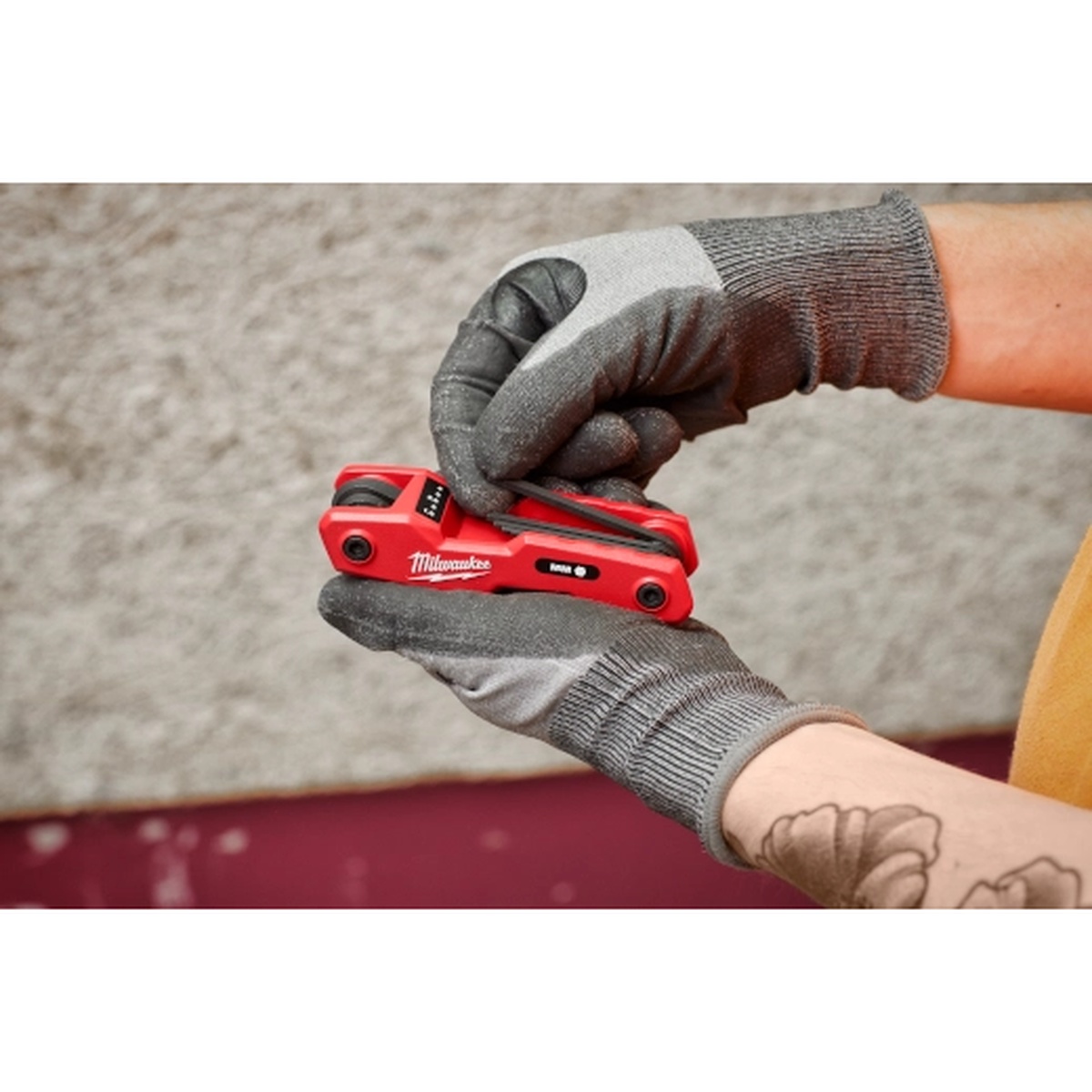 Milwaukee 48-22-2183 17-Piece Folding Hex Key Set - SAE & Metric being opened by a gloved user on a jobsite for quick size selection