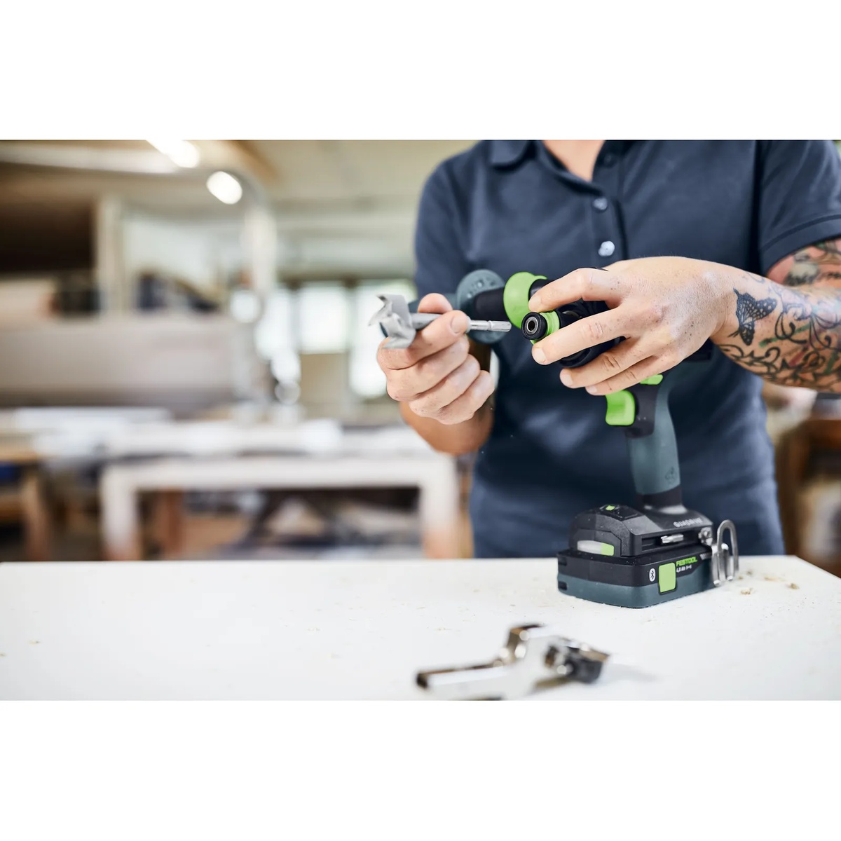 Festool 577627 QUADRIVE TPC 18/4 Cordless Hammer Drill having its chuck changed at a workbench during woodworking setup in a shop