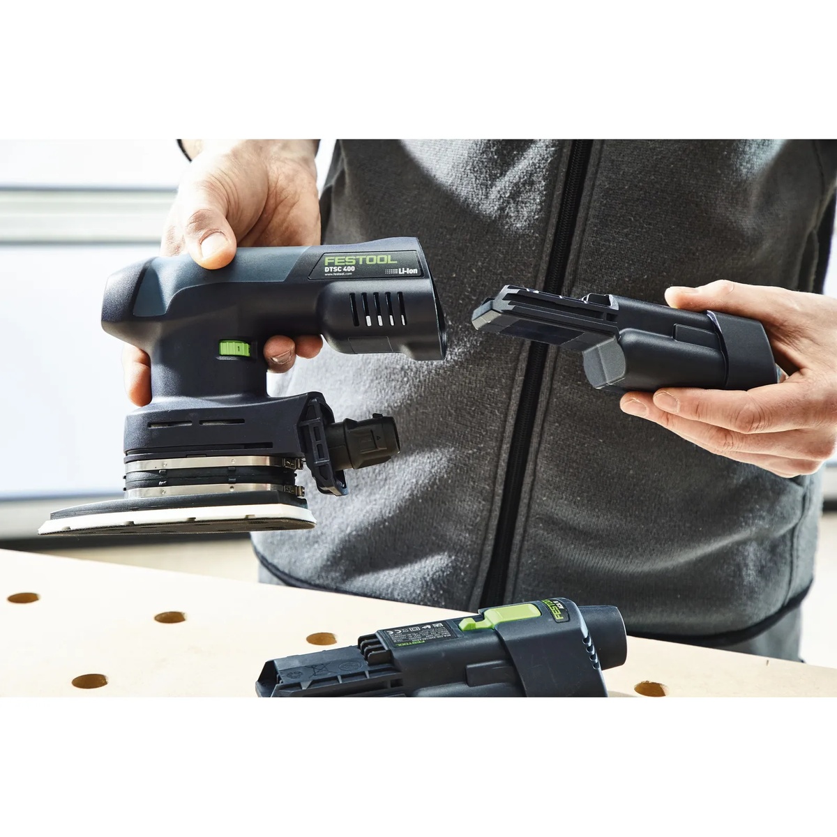 Festool 577705 BP 18 Li 3,0 Ergo I Battery Pack being installed into a Festool cordless sander on a workbench during finish sanding setup