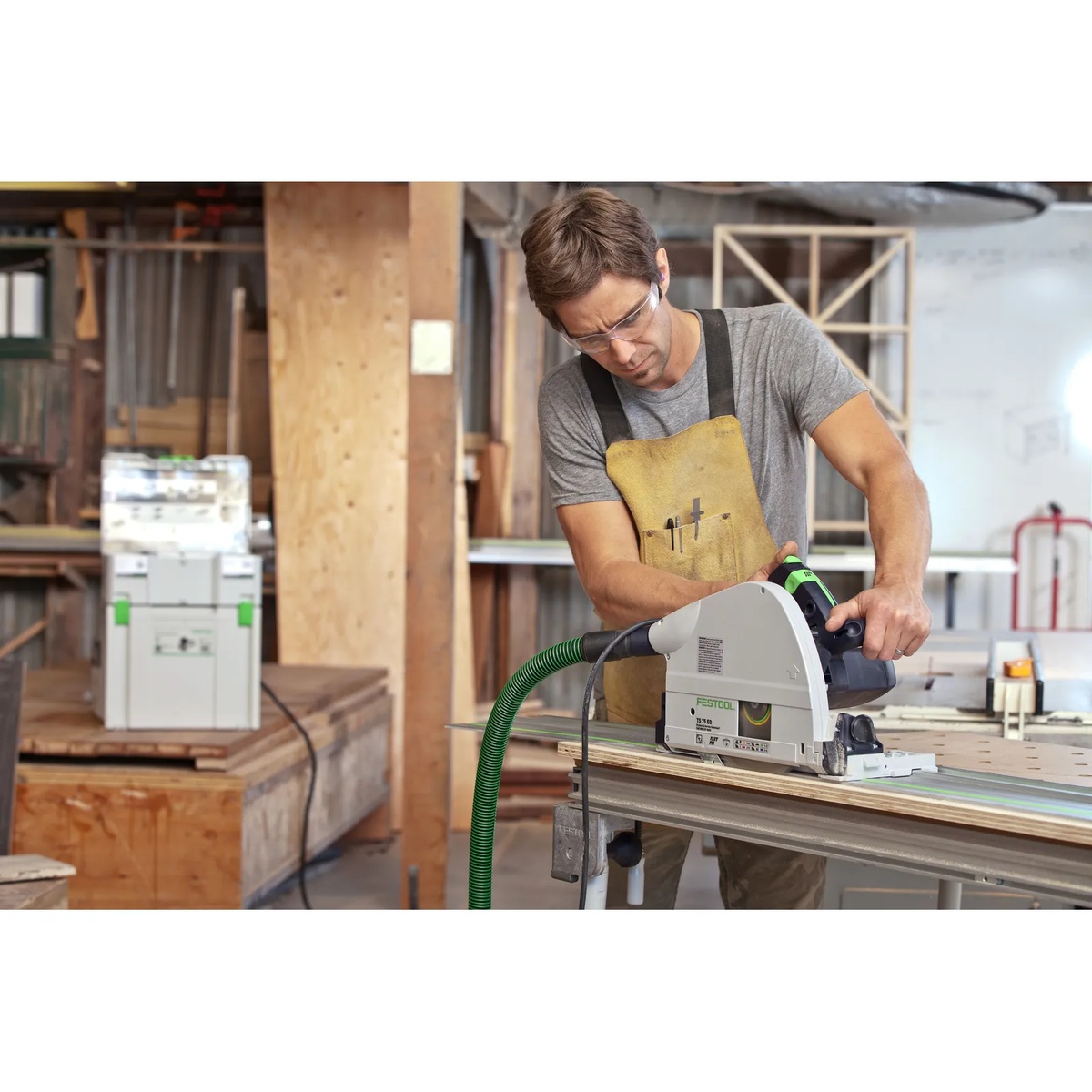Festool TS 75 EQ-F-Plus Plunge Cut Track Saw making a straight plunge cut on a guide rail across sheet material in a woodworking shop