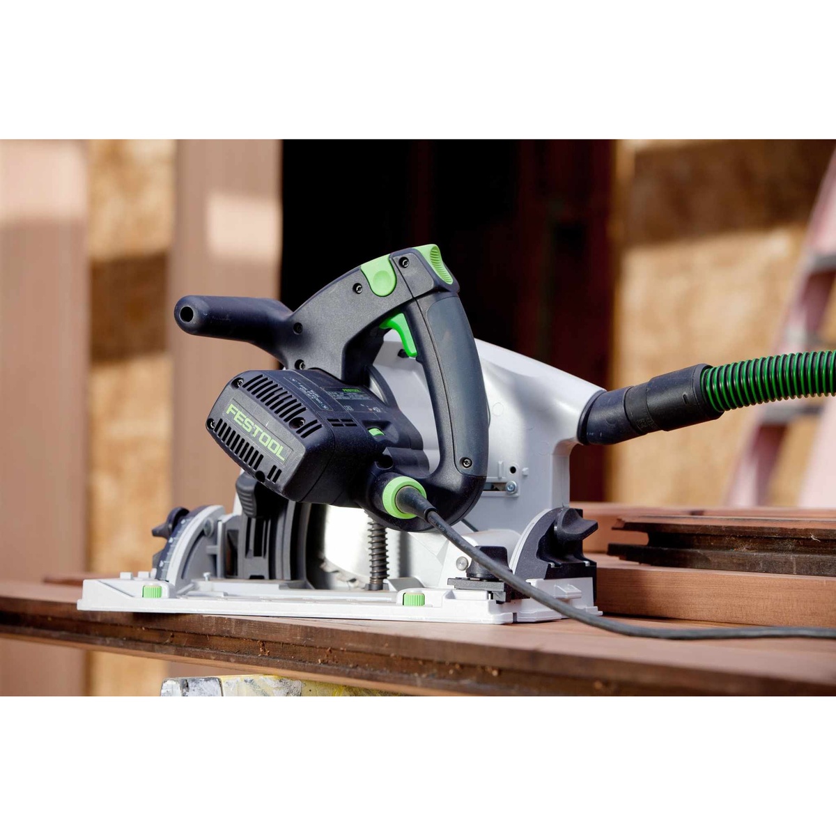 Festool TS 75 EQ Plunge Cut Track Saw connected to dust extraction while cutting wood on a jobsite bench