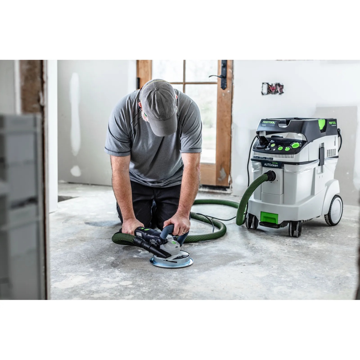 Festool 577048 Corded RENOFIX RG 130 ECI-Plus Surface Restoration Grinder Set grinding a concrete floor indoors with a connected dust extractor during renovation work