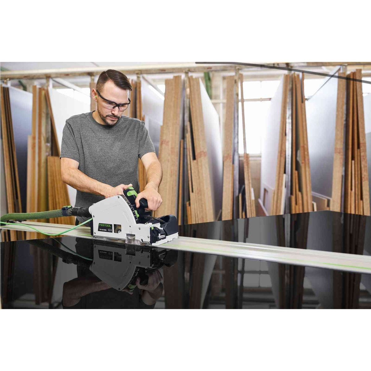 Festool track saw cutting a countertop panel in a kitchen installation setting using a guide rail and dust extraction hose