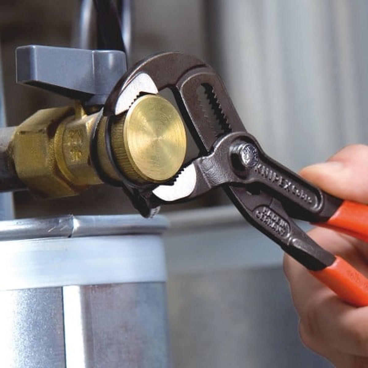 Knipex 00 20 06 US1 3 Pc Cobra Pliers Set gripping a brass valve fitting during plumbing and maintenance work