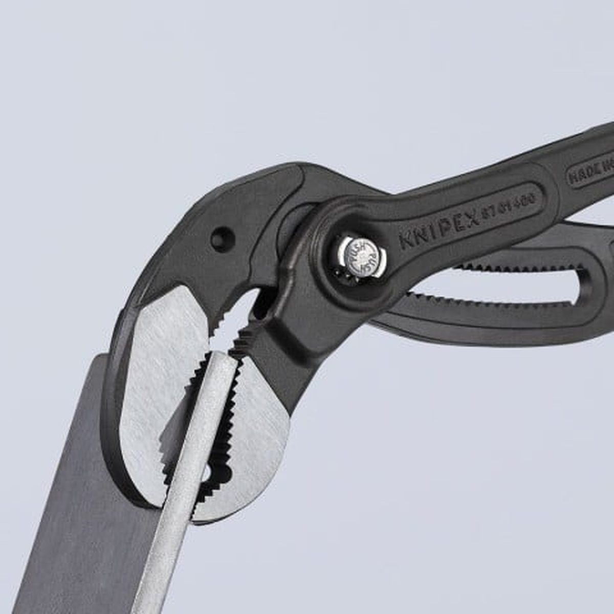 Knipex 87 01 400 US Cobra XL Water Pump Pliers biting onto flat metal stock to show the self-locking jaw grip and hardened teeth