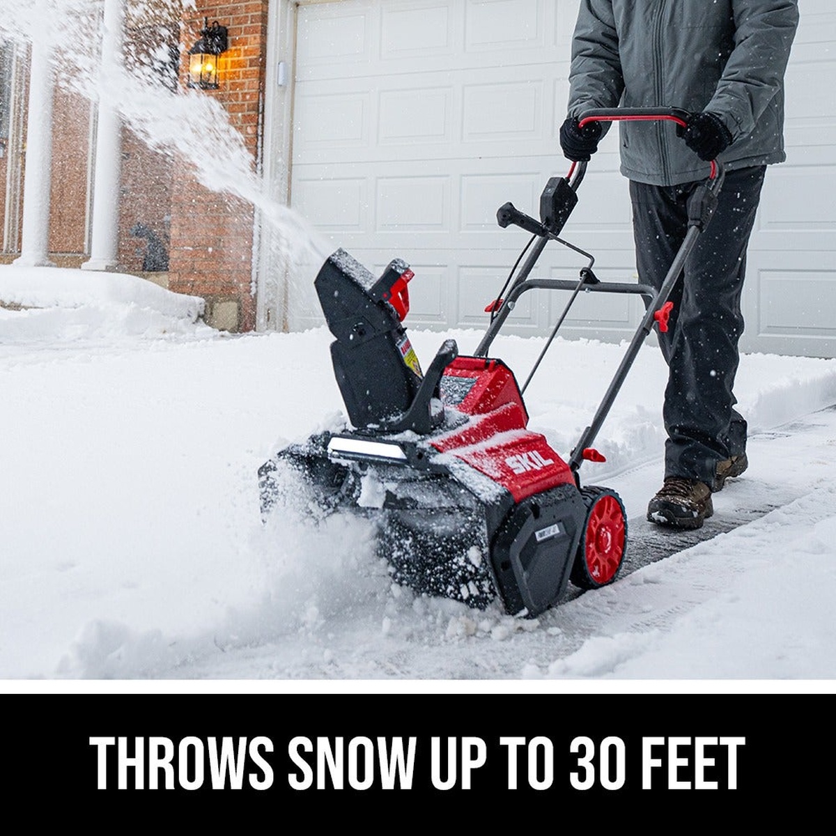 SKIL 40V Brushless 20 In. Single Stage Snow Blower Kit clearing a residential driveway and throwing snow away from the garage during active snow removal