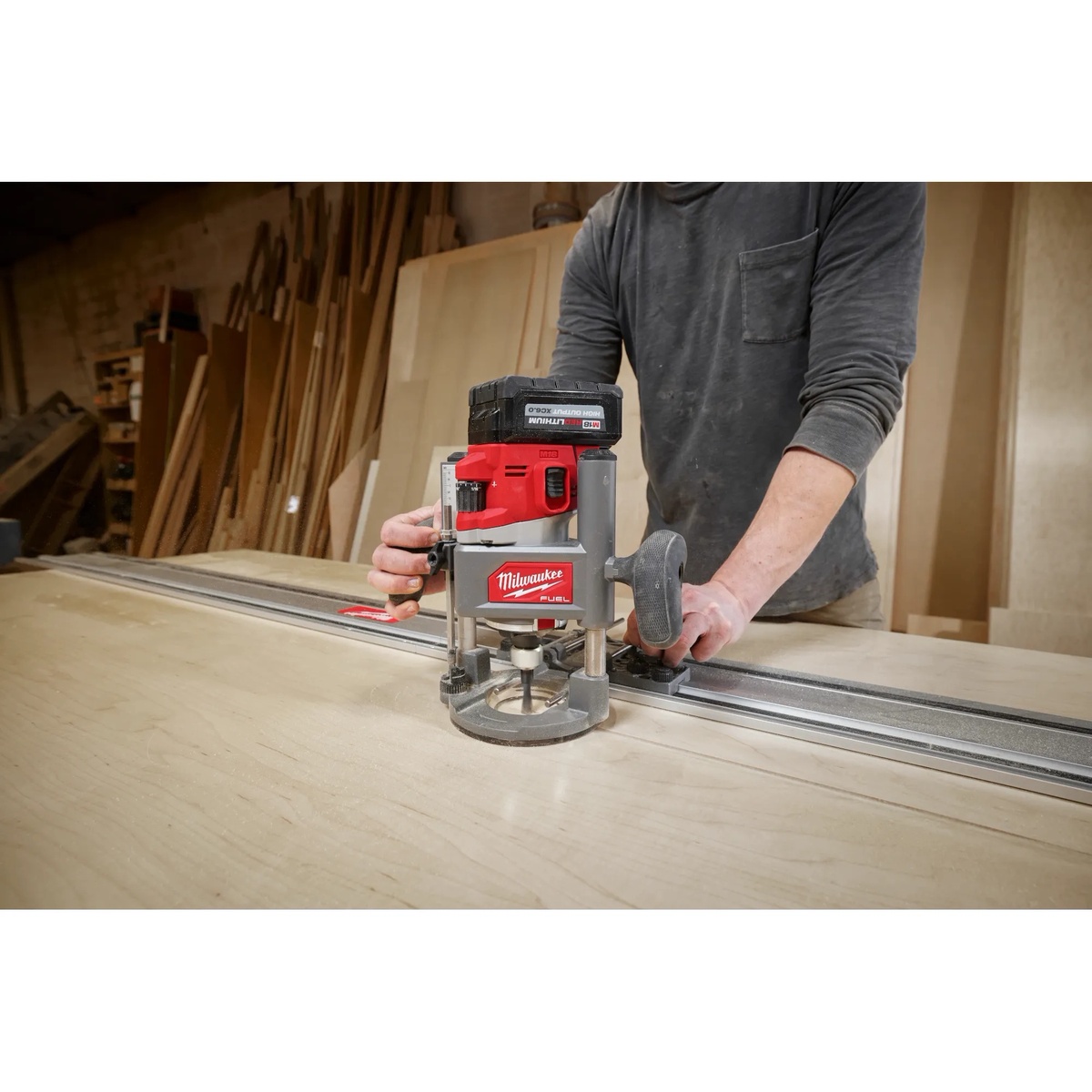 Milwaukee 48-11-2838 Router Guide Rail Adapter guiding a Milwaukee router along a track on a large wood panel in a workshop