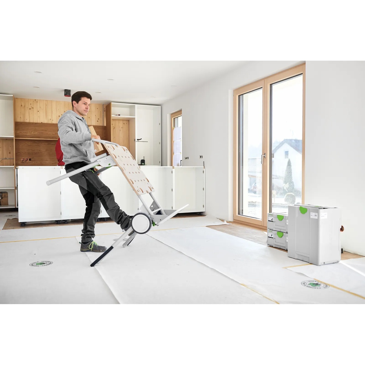 Festool 577001 CSC SYS 50 Cordless Table Saw Underframe UG UG-CSC-SYS being rolled as a hand cart across an indoor jobsite floor during installation work