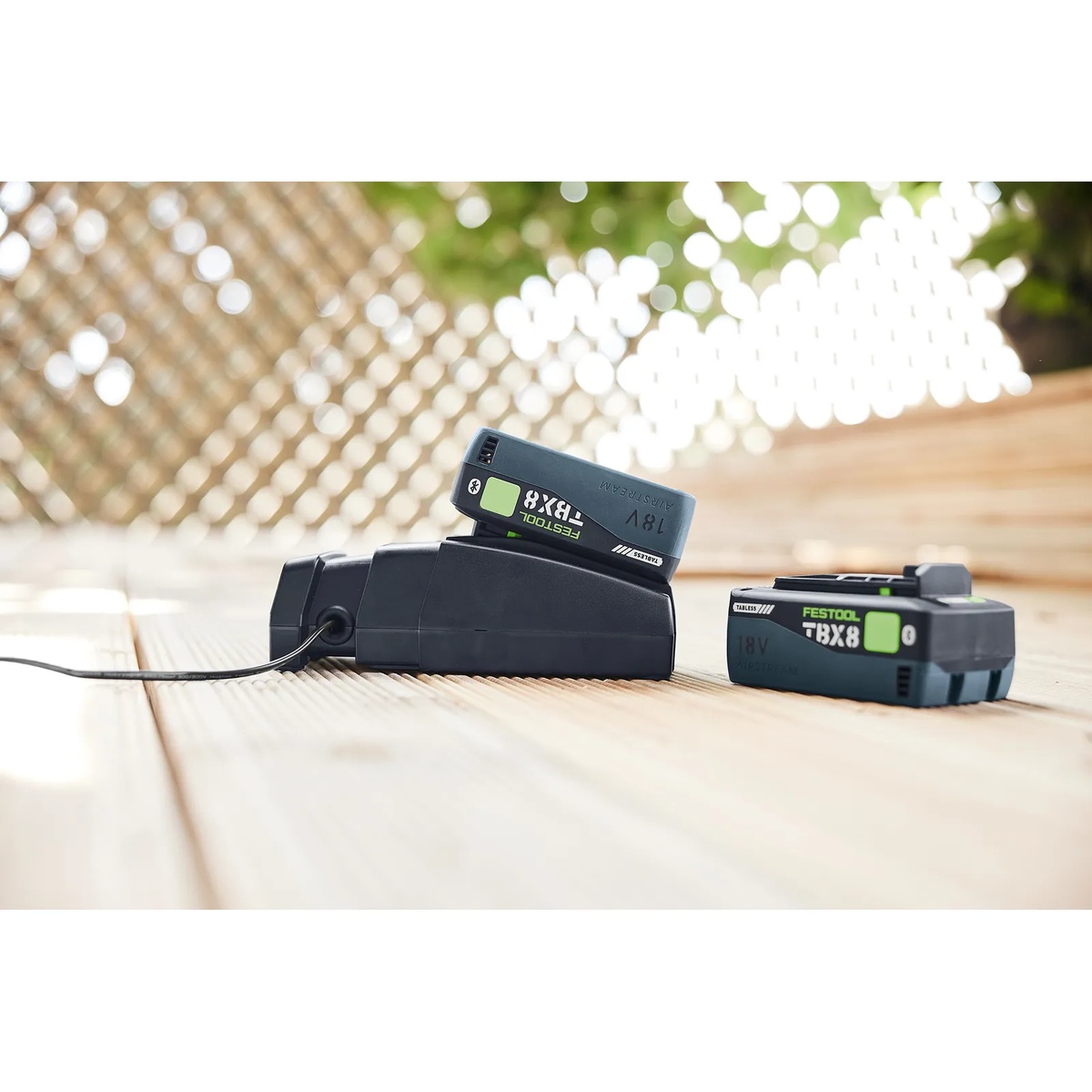 Festool 576954 SCA 16 Rapid Charger charging an 18V battery pack on a deck surface with a second battery nearby