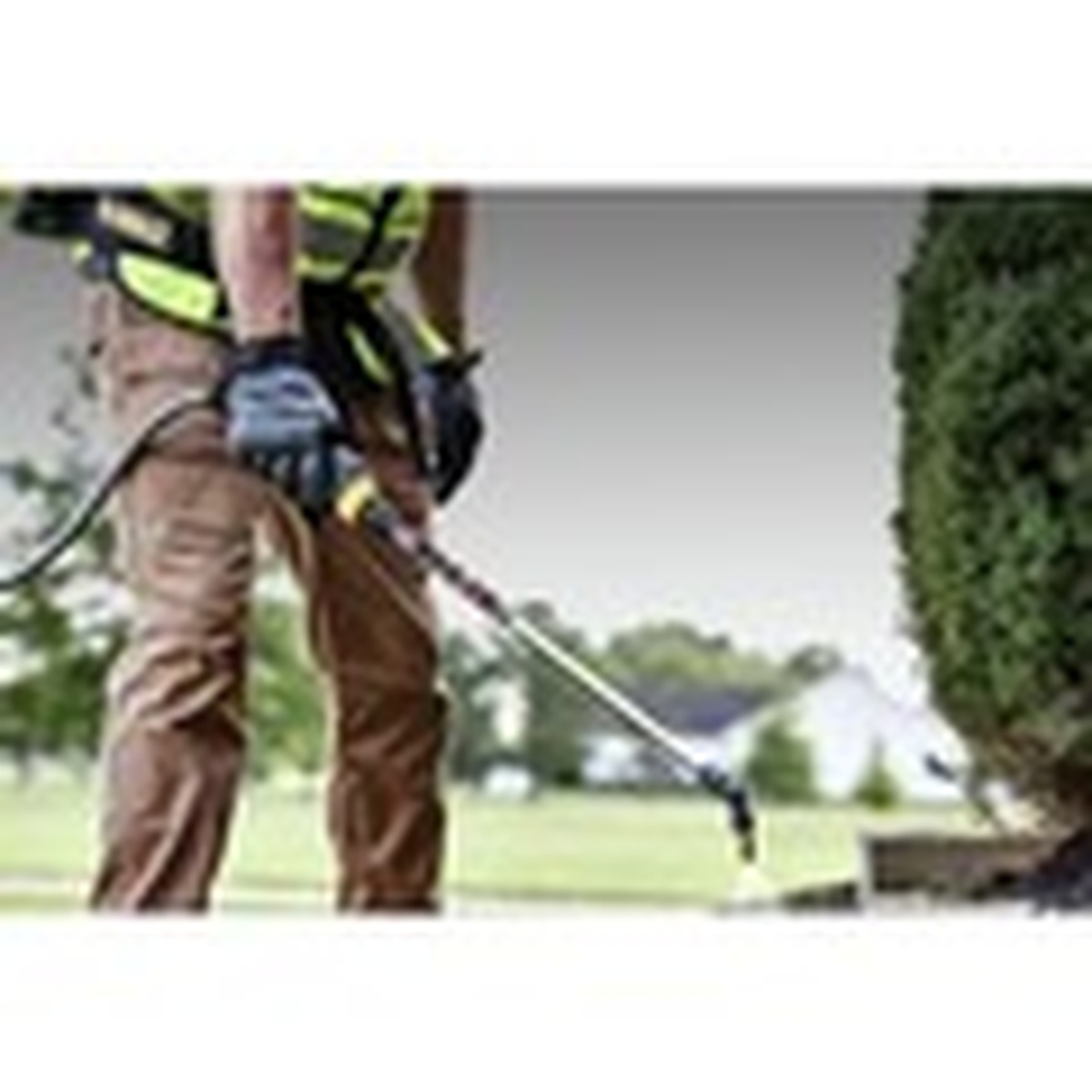 DeWalt DXSP190681B 20V MAX 4-Gallon Backpack Sprayer spraying lawn treatment across grass in outdoor property maintenance work