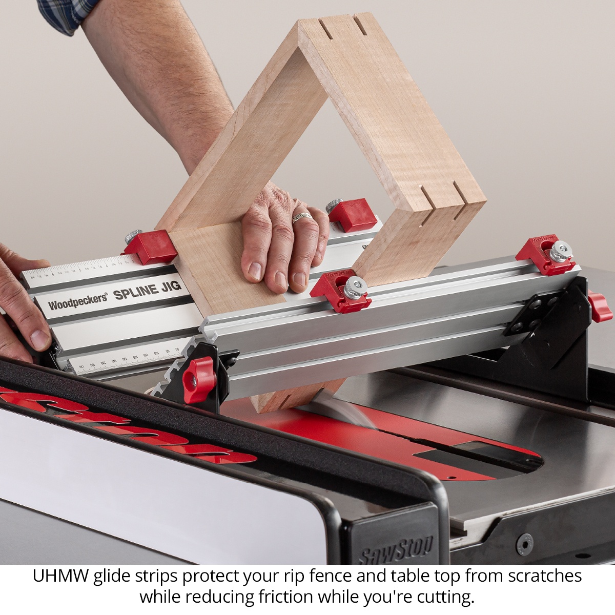 Woodpeckers Spline Jig supporting a wood frame on a table saw with UHMW glide strips contacting the fence and tabletop during a spline cutting setup