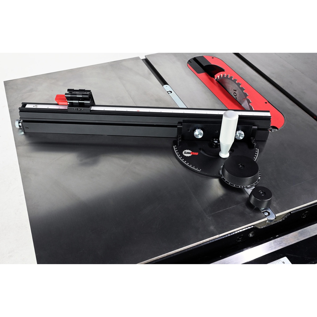 SawStop Revolution Miter Gauge mounted on a table saw showing the fence, flip stop, and miter bar interface for accurate crosscut alignment