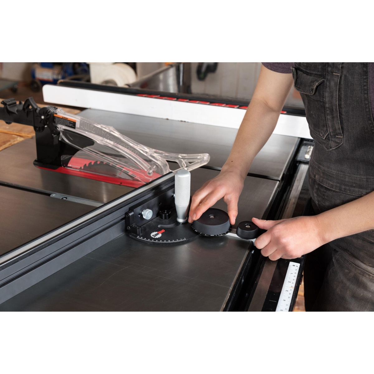 SawStop Revolution Miter Gauge being adjusted on a table saw in a woodworking shop while setting the angle dial for precise crosscut work